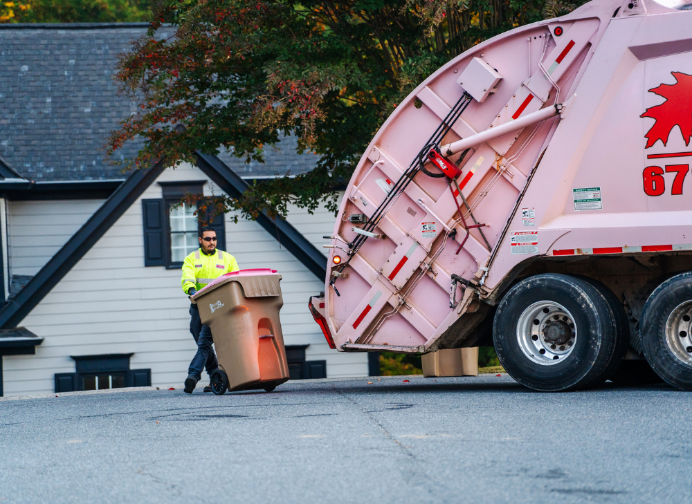 Worker Rolling Trash Bin Toward Garbage Truck